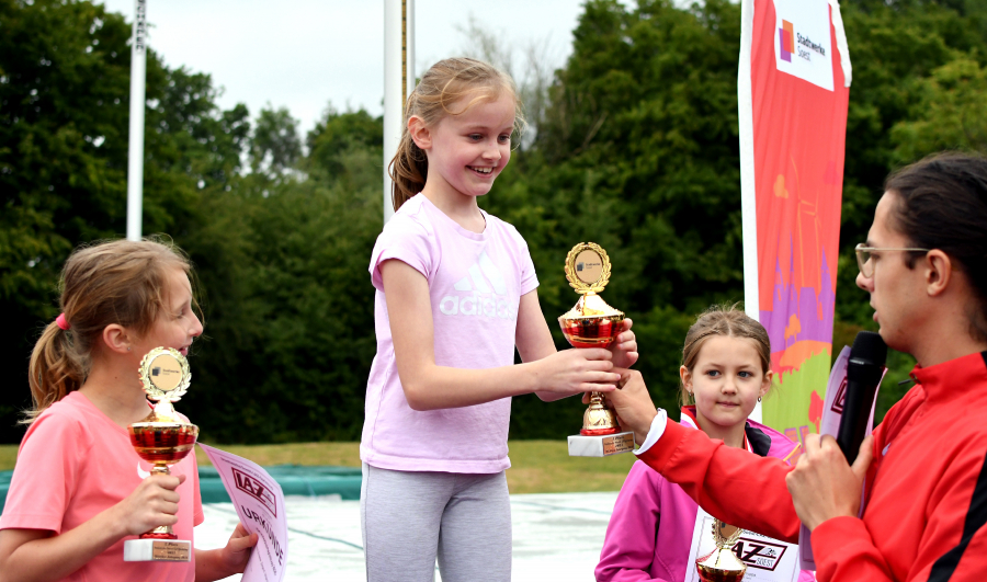 Freudestrahlend nimmt Anastasia Wolf den Siegerpokal aus den Händen von Florian Wendt, dem stellvertretenden sportlichen Leiter des LAZ Soest entgegen. Die Georg-Schülerin gewann in der Altersklasse 2016 vor Lara Hinkelmann (links, Georg) und Luisa Kruppa (rechts, Bruno). Foto: Bottin